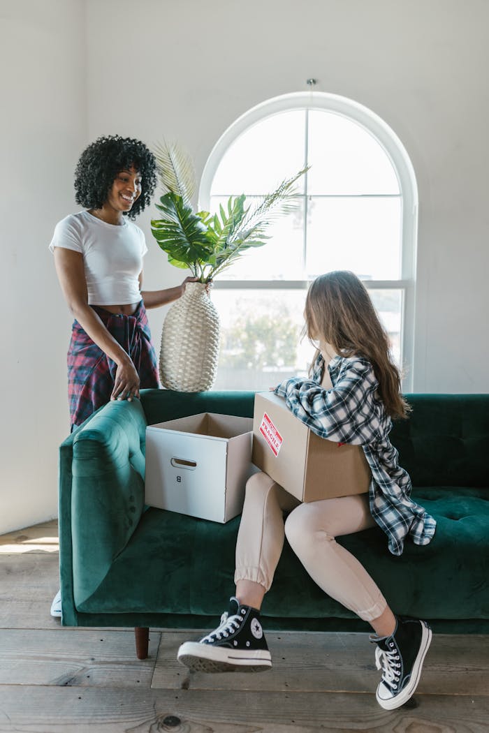 Two young women unpack moving boxes in their new home.