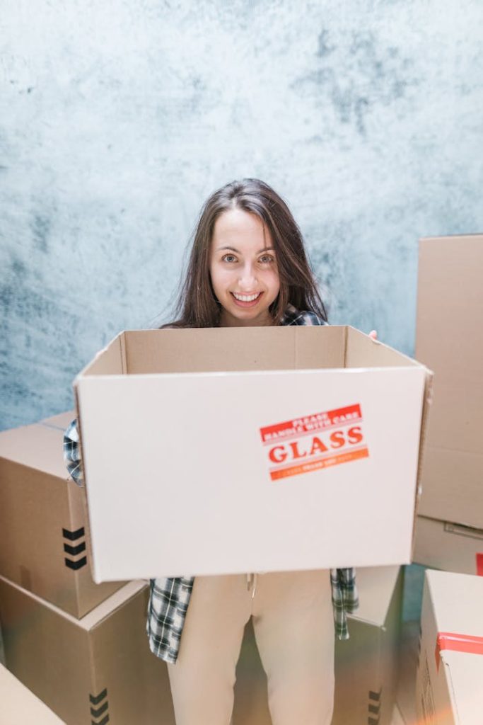 Smiling woman holding a box marked fragile while moving into her new home.